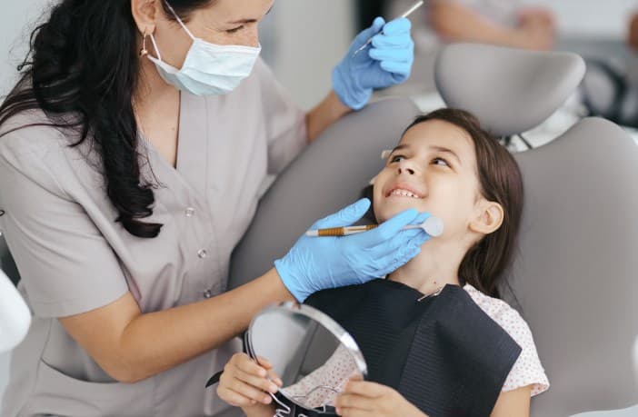Dentista atendendo uma criança com um sorriso