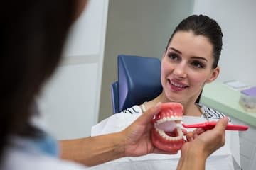 Paciente sendo atendido com um modelo dental em demonstração.